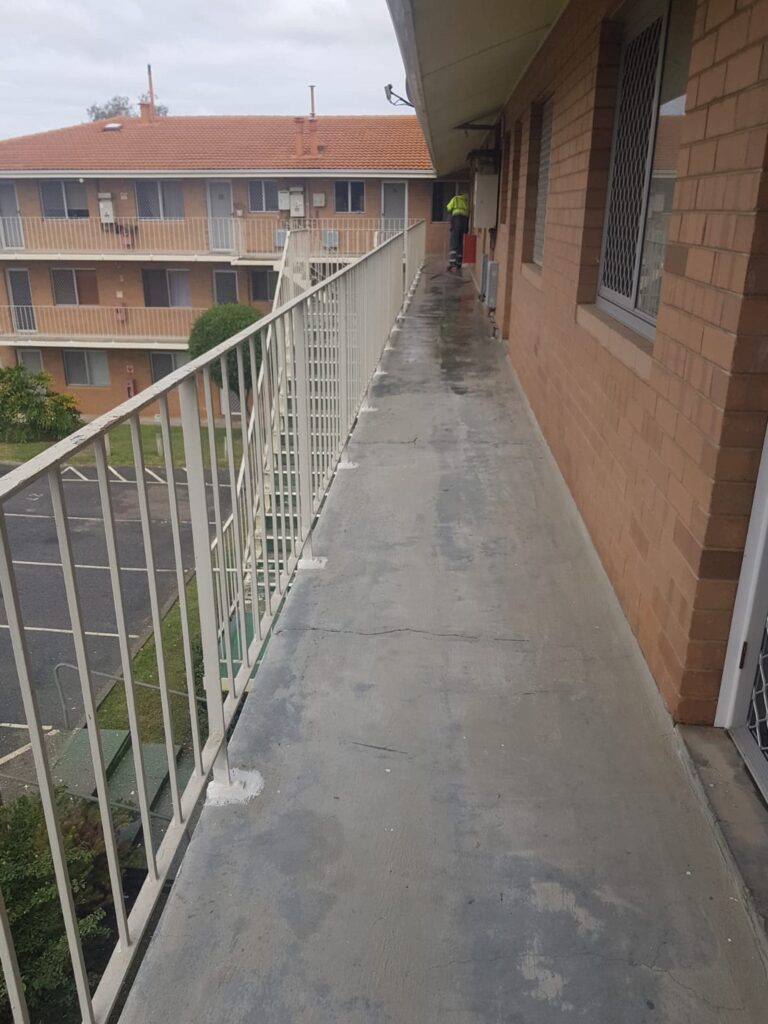 A balcony with a door and railing. Concrete spalling and corroded handrailing may require Corrosion Control Australia services